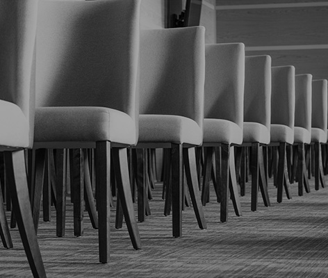 Gray textile chairs with brown wooden legs stand in a straight l